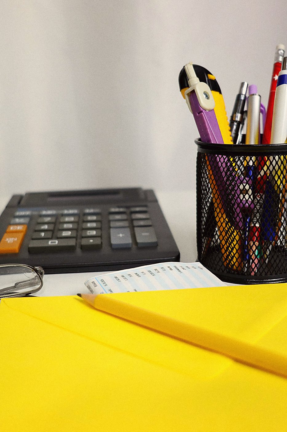 A calculator, pens and an envelope on an office desk