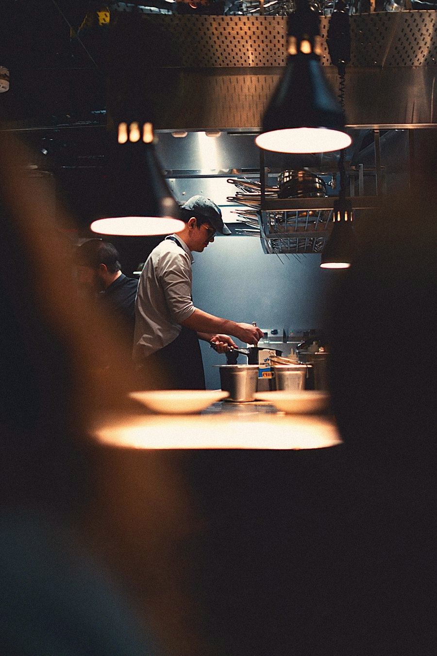A cook working in a dim, warm kitchen
